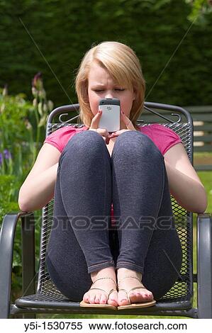Stock Photography - Teenage girl texting on a mobile phone, England, MR PR. Fotosearch
