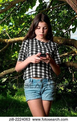 Stock Image - Teenage girl texting on her mobile phone.. Fotosearch