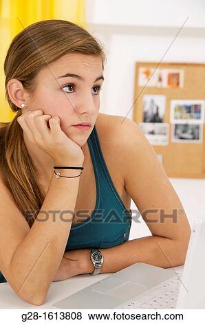 Teenage Girl thinking and doing her homework at home with a computer, looking bored View Large Photo Image Stock Photo - Teenage Girl thinking and doing her homework at home with a computer, looking bored. Fotosearch