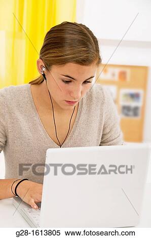 Teenage girl using her computer and listening to music at home View Large Photo Image Stock Photography - Teenage girl using her computer and listening to music at home. Fotosearch