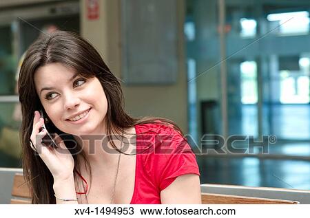 Stock Image - Teenage girl waiting in train station, talking on cell phone. Fotosearch