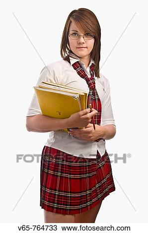 Stock Image - Teenage girl wearing her school uniform holding her books. Fotosearch
