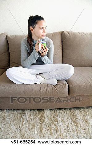Teenage girl with a cup in the couch thoughtful View Large Photo Image Picture - Teenage girl with a cup in the couch thoughtful. Fotosearch