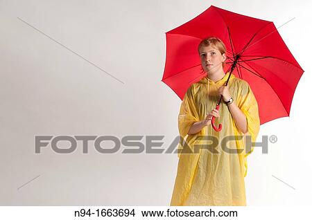 Teenage girl with yellow rain gear protected with red umbrella. View Large Photo Image Picture - Teenage girl with yellow rain gear protected with red umbrella.. Fotosearch