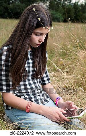 Stock Image - Teenage with a tablet in the park.. Fotosearch