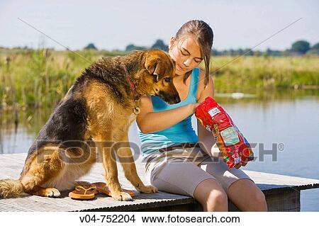Teenaged girl and her pet dog eating potato chips outdoors at a lake View Large Photo Image Picture - Teenaged girl and her pet dog eating potato chips outdoors at a lake. Fotosearch