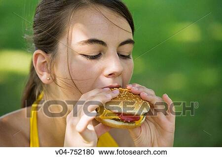 Teenaged girl biting into a hamburger outdoors View Large Photo Image Stock Image - Teenaged girl biting into a hamburger outdoors. Fotosearch