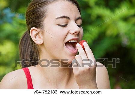 Teenaged girl eating a strawberry outdoors View Large Photo Image Stock Image - Teenaged girl eating a strawberry outdoors. Fotosearch