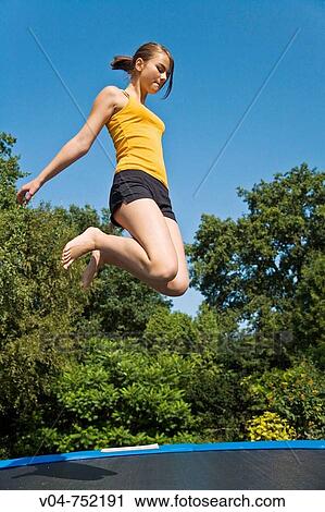 Teenaged girl jumping on a trampoline outdoors View Large Photo Image Stock Image - Teenaged girl jumping on a trampoline outdoors. Fotosearch
