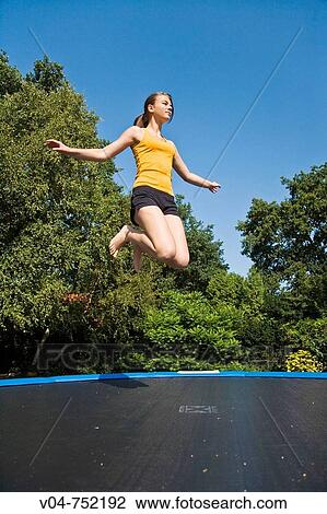 Teenaged girl jumping on a trampoline outdoors View Large Photo Image Stock Image - Teenaged girl jumping on a trampoline outdoors. Fotosearch