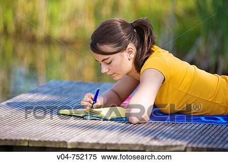 Teenaged girl lying on a footbridge and writing in her diary looking thoughtful View Large Photo Image Stock Photography - Teenaged girl lying on a footbridge and writing in her diary looking thoughtful. Fotosearch