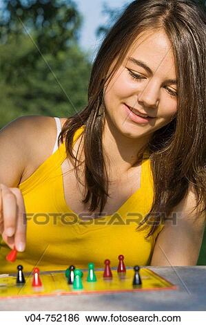 Teenaged girl playing a board game outdoors in a garden View Large Photo Image Stock Photograph - Teenaged girl playing a board game outdoors in a garden. Fotosearch
