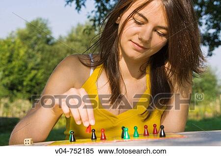 Teenaged girl playing a board game outdoors in a garden View Large Photo Image Stock Photography - Teenaged girl playing a board game outdoors in a garden. Fotosearch