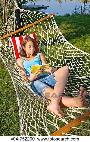 Teenaged girl reading a book in a hammock outdoors in a garden View Large Photo Image Stock Image - Teenaged girl reading a book in a hammock outdoors in a garden. Fotosearch