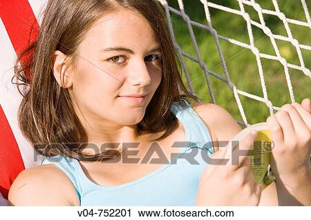 Teenaged girl reading a book in a hammock and smiling at the camera outdoors View Large Photo Image Stock Image - Teenaged girl reading a book in a hammock and smiling at the camera outdoors. Fotosearch