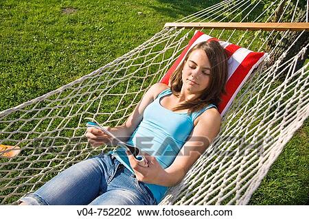 Teenaged girl reading a magazine in a hammock outdoors View Large Photo Image Stock Image - Teenaged girl reading a magazine in a hammock outdoors. Fotosearch