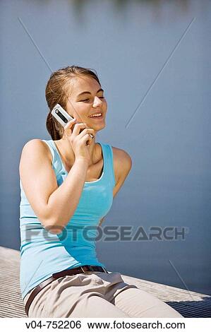 Teenaged girl talking and smiling on her cell phone outdoors at a lake View Large Photo Image Stock Photograph - Teenaged girl talking and smiling on her cell phone outdoors at a lake. Fotosearch