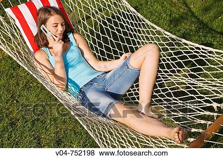 Teenaged girl talking on her cell phone in a hammock outdoors View Large Photo Image Stock Photo - Teenaged girl talking on her cell phone in a hammock outdoors. Fotosearch