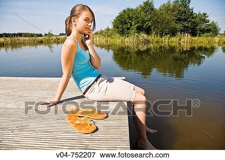 Teenaged girl talking on her cell phone outdoors at a lake View Large Photo Image Stock Photo - Teenaged girl talking on her cell phone outdoors at a lake. Fotosearch
