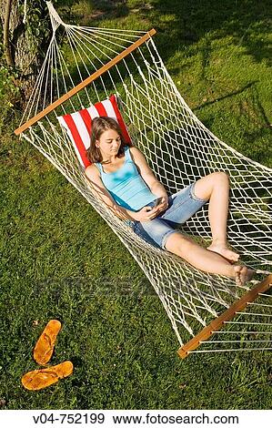 Stock Photo - Teenaged girl writing a SMS message in a hammock outdoors. Fotosearch
