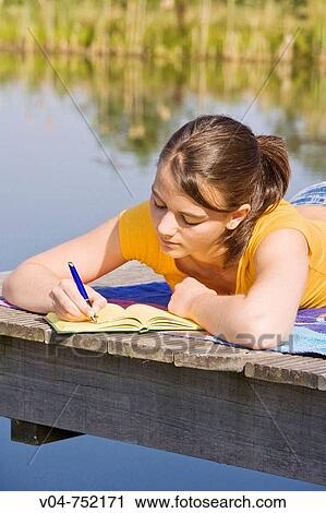 Teenaged girl writing in her diary outdoors looking thoughtful View Large Photo Image Stock Image - Teenaged girl writing in her diary outdoors looking thoughtful. Fotosearch