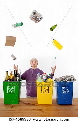 Stock Image - Teenager juggling recycling domestic waste. Fotosearch