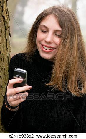 Stock Image - Teenager using her mobile phone. Fotosearch