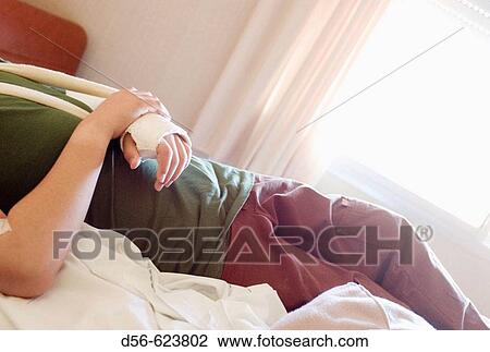 Stock Image - Teenager with broken arm lying in hospital bed. Fotosearch