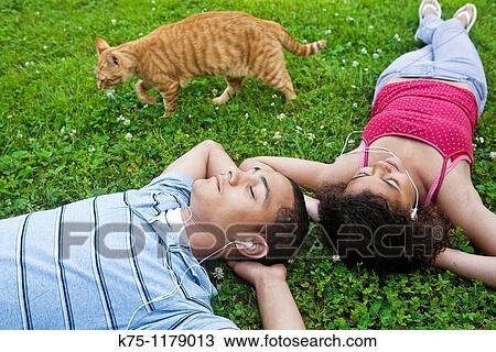 Stock Image - Teenagers listening to music and cat walking by. Fotosearch