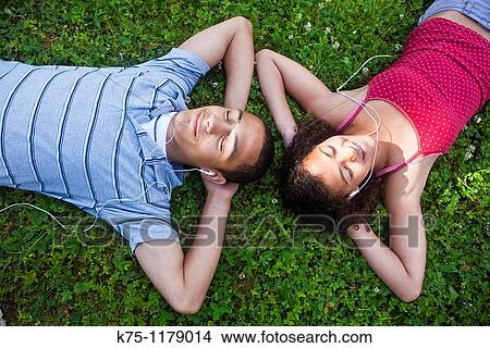 Picture - Teenagers listening to music lying on the lawn. Fotosearch
