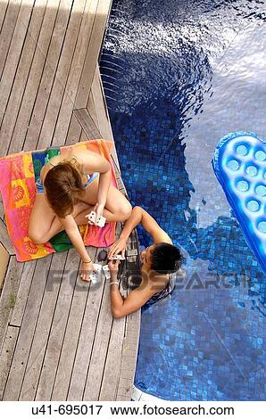Stock Photo - Teenagers playing cards by the pool. Fotosearch