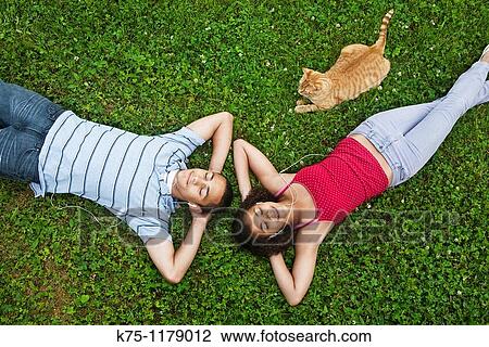 Stock Image - Teenagers relaxing with their pet cat and music. Fotosearch