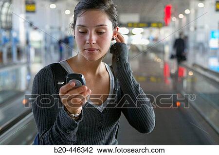 Stock Image - Teengirl using cell phone in Brussels airport. Belgium. Fotosearch