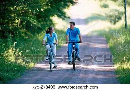 Stock Image - Teens biking on country road. Fotosearch