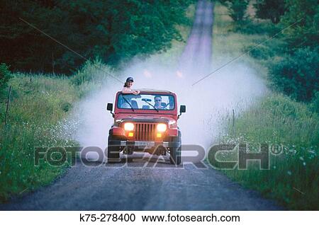 Stock Image - teens traveling country road in jeep. Fotosearch