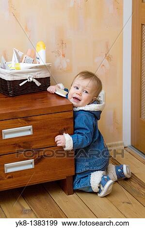 Stock Photo - Ten Month Old Baby Holding Hairbrush by Bedside Tabel. Fotosearch