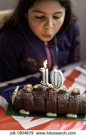 Stock Photo - Ten year old girl, blows candles on birthday cake. Fotosearch