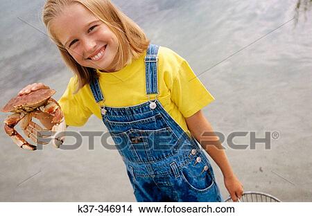 Ten years old girl on beach proudly showing the crab caught while crabbing on vacation. View Large Photo Image Picture - Ten years old girl on beach proudly showing the crab caught while crabbing on vacation.. Fotosearch