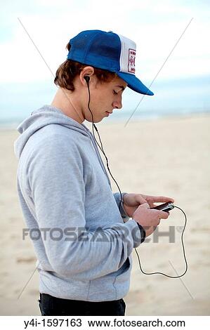 Tennager listening music to earphones and typing a message View Large Photo Image Stock Image - Tennager listening music to earphones and typing a message. Fotosearch