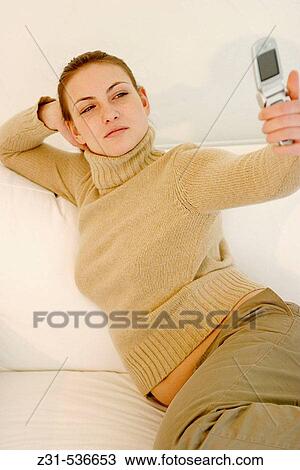 Stock Image - Teresa, Cell phone, Photographing, Sitting, Sofa, Warm clothes. Fotosearch