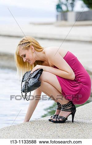 Stock Photo - Testing water temperature young attractive woman. Fotosearch