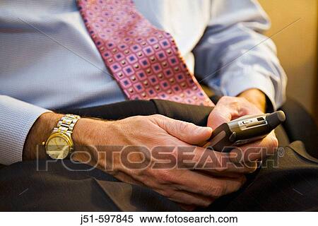TEXAS Austin Male executive enter text using keypad on cellular telephone while working in hotel room, left handed, watch View Large Photo Image Stock Photography - TEXAS Austin Male executive enter text using keypad on cellular telephone while working in hotel room, left handed, watch. Fotosearch