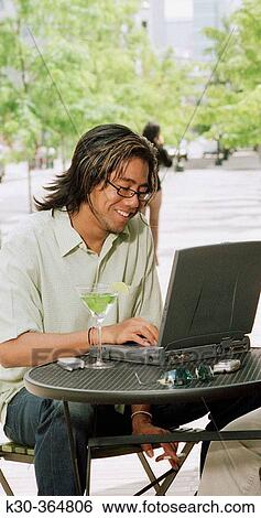 Thai man using computer at outdoor restaurant View Large Photo Image Stock Photograph - Thai man using computer at outdoor restaurant. Fotosearch