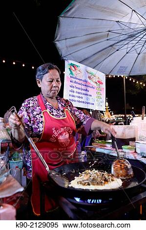 Stock Photography - Thai woman preparing Pad Thai - fried Thai noodles - on the night market, Mae Hong Son, Thailand, Southeast Asia.. Fotosearch