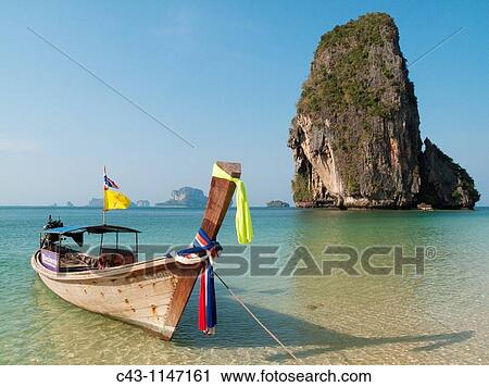 Thailand - Long-tail boat at the sandy Phranang Beach and limestone cliffs in the Andaman Sea Phranang Peninsula, Krabi province, Southern Thailand View Large Photo Image Stock Image - Thailand - Long-tail boat at the sandy Phranang Beach and limestone cliffs in the Andaman Sea Phranang Peninsula, Krabi province, Southern Thailand. Fotosearch