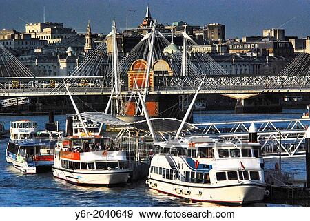 Thames cruising boats at the London Eye Pier, in the heart of London, England,, on the River Thames, on a very sunny day, with Hungerford Bridge in the background. View Large Photo Image Stock Photo - Thames cruising boats at the London Eye Pier, in the heart of London, England,, on the River Thames, on a very sunny day, with Hungerford Bridge in the background.. Fotosearch