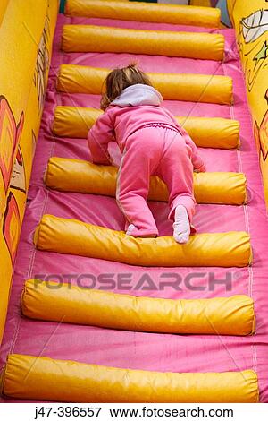 The back of a 3 year old girl climbing up huge inflatable pink steps View Large Photo Image Stock Photo - The back of a 3 year old girl climbing up huge inflatable pink steps. Fotosearch