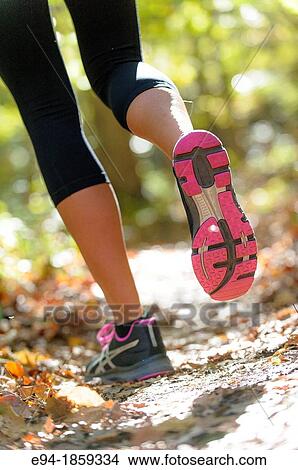 The back view of legs of a woman wearing work-out clothing jogging on a trail in a forest setting in the fall View Large Photo Image Picture - The back view of legs of a woman wearing work-out clothing jogging on a trail in a forest setting in the fall. Fotosearch