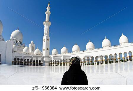 Picture - The beautiful interior of the white Sheikh Zayed Grand Mosque in Abu Dhabi in the UAE the worlds 8th largest Muslim mosque in the world with Muslim tourist in United Arab Emirates.. Fotosearch