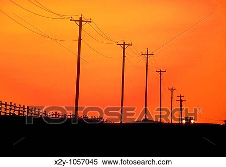 The distant headlights of a lone aproaching car as it travels over a country road, past an expanse of telephone lines and poles in silhouette under a sunset sky View Large Photo Image Stock Photography - The distant headlights of a lone aproaching car as it travels over a country road, past an expanse of telephone lines and poles in silhouette under a sunset sky. Fotosearch